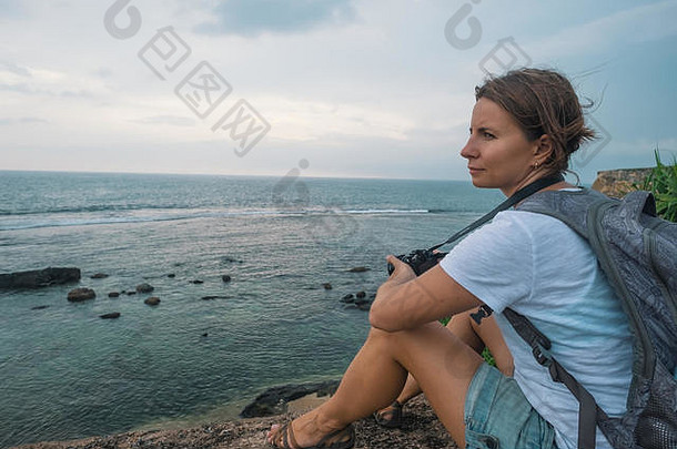 一位白人妇女坐在石头上，望着大海。主动行驶中的静力矩概念