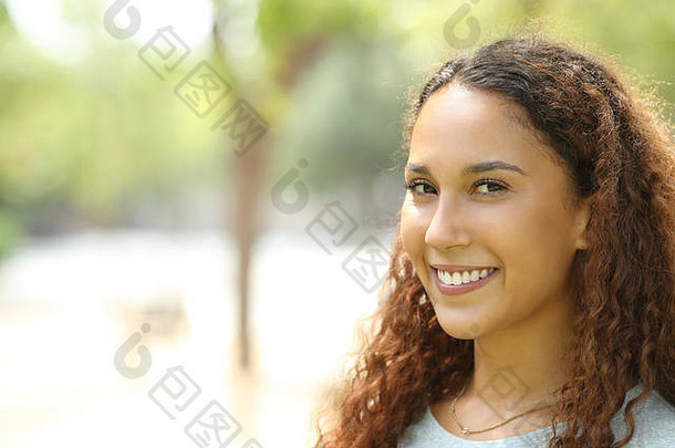 在公园里，一位美丽的混血女子带着完美的微笑看着相机