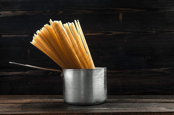 意大利面意大利面复古的铝锅处理黑暗木桌子上表面