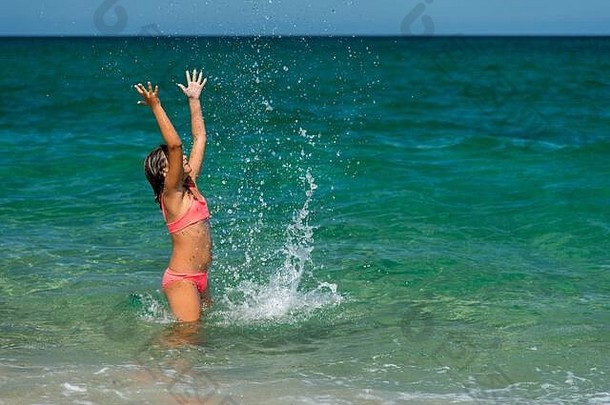 女孩在海边享受沐浴和泼水的乐趣-度假理念，空间