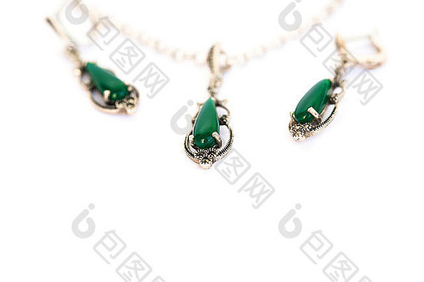 白色背景上镶嵌绿色宝石的项链和耳环。
