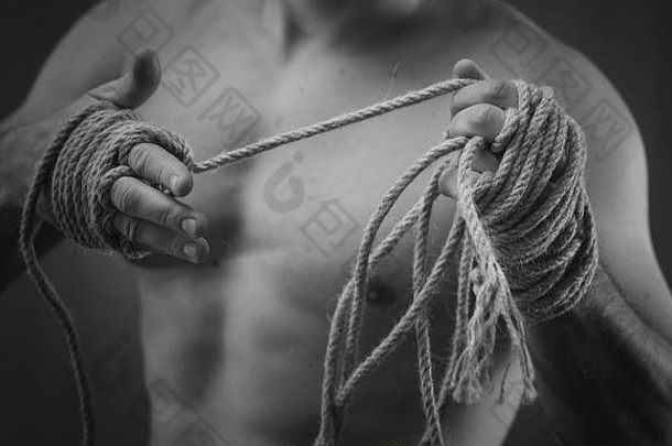 特写镜头：一名年轻的泰国拳击手在比赛或训练前手上缠着麻绳。黑白风格