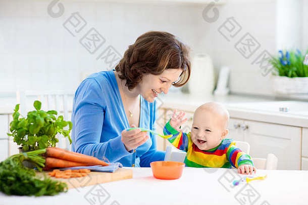 母亲喂养孩子。给小孩子的第一种固体食物。新鲜的有机胡萝卜做蔬菜午餐。婴儿断奶。妈妈和小男孩吃蔬菜。堆