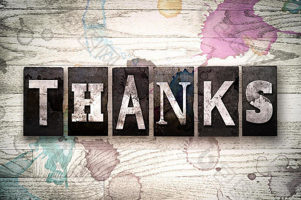 “谢谢”这个词是用老式的脏金属活版印刷字体写的，背景是白色的木头，上面有墨水和油漆污渍。