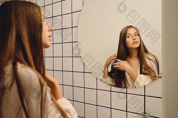 年轻的美丽的女人白色衣服如痴如梦镜子刷牙头发浴室