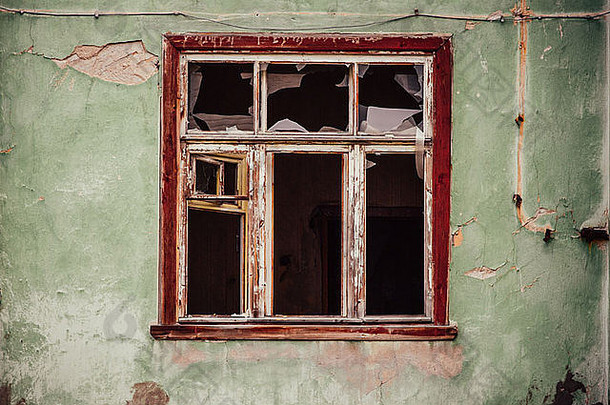 破烂的玻璃窗和破旧的木架在垃圾墙上，毁坏了房子