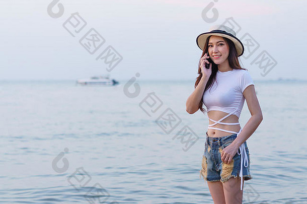 美丽的女人在海滩上使用手机