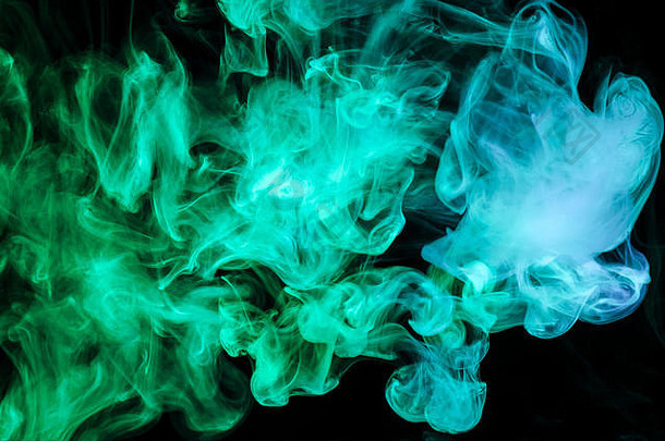 黑色孤立背景上浓浓的绿色和蓝色的彩色烟雾。来自vape烟雾的背景