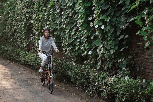 亚洲妇女戴头盔骑折叠自行车