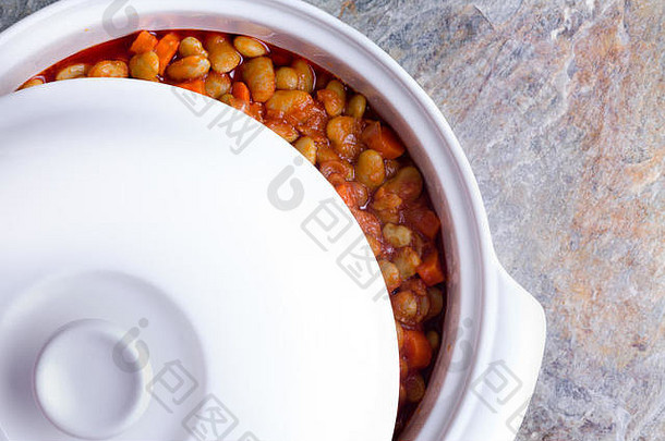 美味可口的利马豆砂锅，胡萝卜在白色陶瓷砂锅中冷却，盖子移到一边观看
