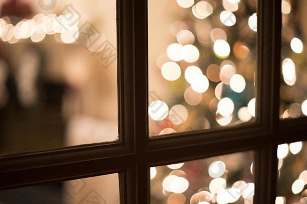 一张博克人的照片在晚上透过窗户窥视为圣诞节装饰的客厅。