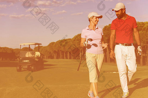 年轻的夫妇走洞高尔夫球男人。携带高尔夫球袋