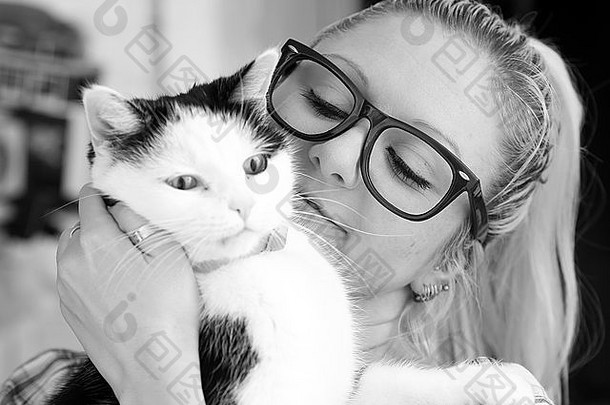 美丽的年轻女子戴着一副大眼镜，带着一只黑白相间的中年猫。2016年4月5日