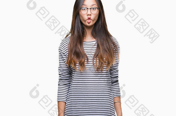 年轻的亚洲女人戴着眼镜在孤立的背景下用嘴唇做鱼脸，疯狂而滑稽的姿势。滑稽的表情。