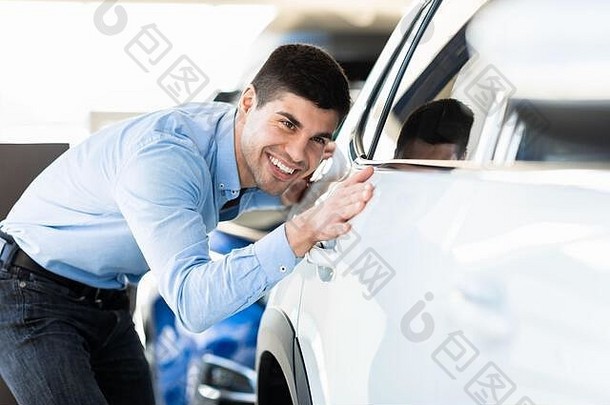 快乐的家伙在经销商展厅触摸他的汽车