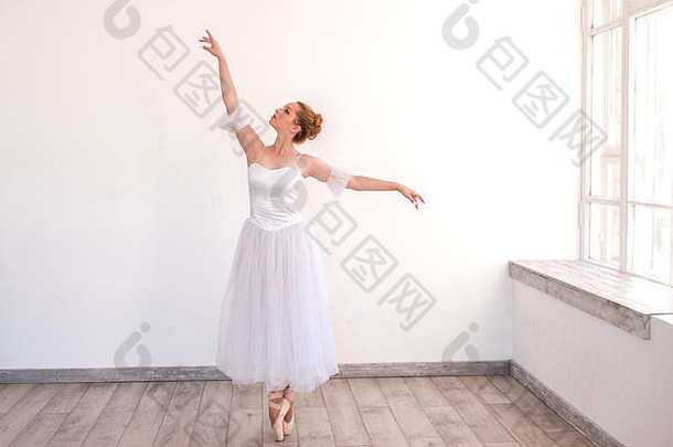 年轻的优雅的芭蕾舞女演员跳舞白色工作室