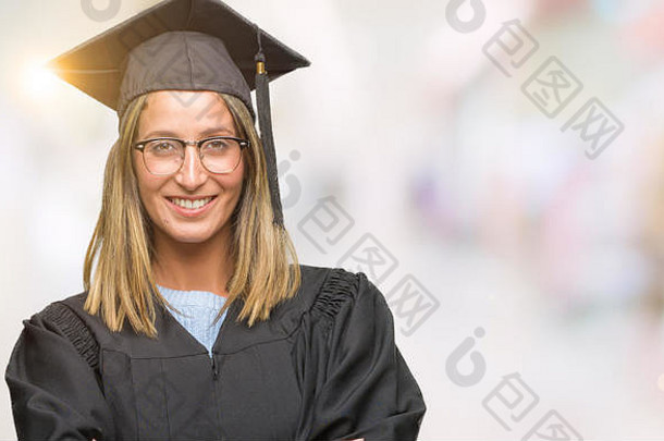 年轻漂亮的女人穿着毕业制服，脸上挂着幸福的笑容，双臂交叉看着摄像机。积极的人。