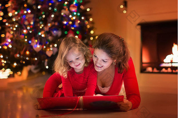 平安夜，母亲和女儿在壁炉旁看书。一家人带着孩子庆祝圣诞节。