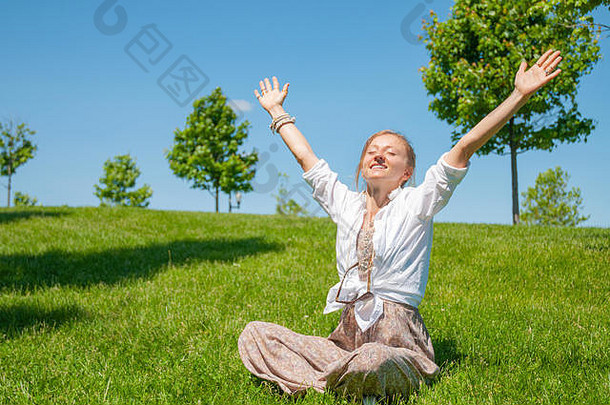 自由幸福概念美丽的女人嬉皮风格提高手坐着草享受阳光明媚的一天公园夏天快乐时刻