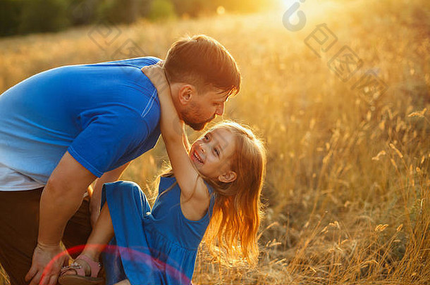 家庭价值观。女儿挂在父亲的脖子上。<strong>日</strong>落时他们正在田野里散步。<strong>亲子</strong>之乐。太阳光。