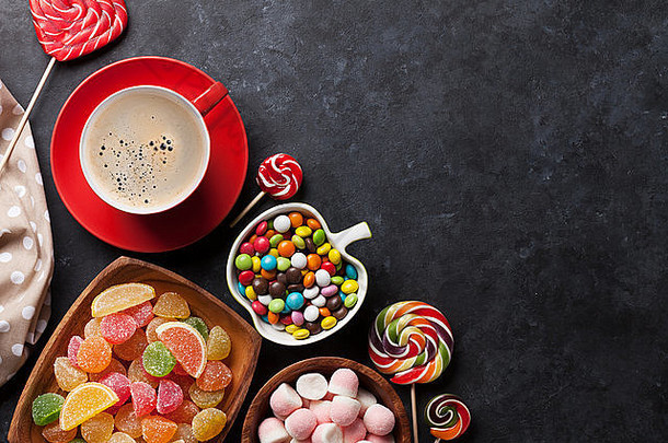 咖啡，彩色糖果，果冻和果酱在石头背景上。具有空间的俯视图