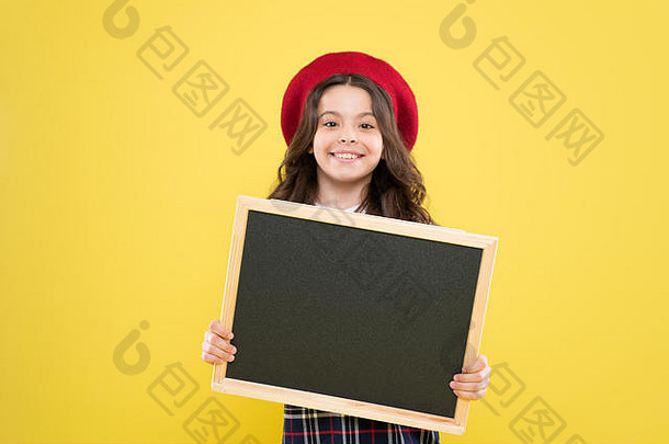 戴法国贝雷帽的小女孩。广告一个拿着空黑板的孩子。黄色背景上的巴黎小孩。戴贝雷帽的卷发快乐女孩。你的广告很受欢迎。广告牌。