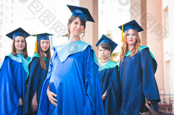 一群年轻的女毕业生。女毕业生在大学毕业生的背景下微笑着。教育、毕业和知识的概念