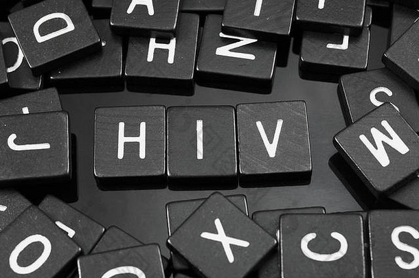 黑色字母瓷砖在反光背景上拼写单词HIV