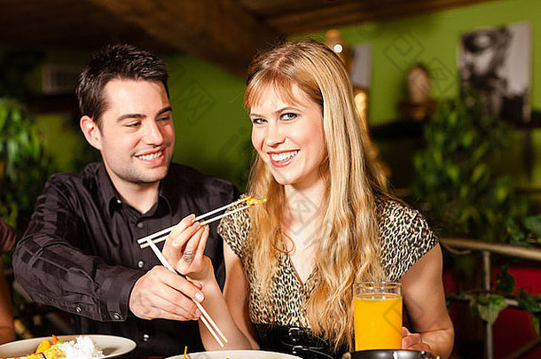 在泰国餐馆吃饭的年轻人，他们用筷子吃饭