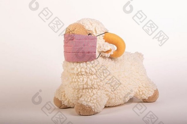 柔软的玩具羊戴着的口罩，白色背景，特写镜头