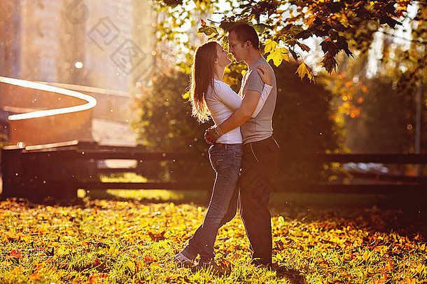 恋爱中的年轻夫妇，站在树下，在公园里拥抱夕阳
