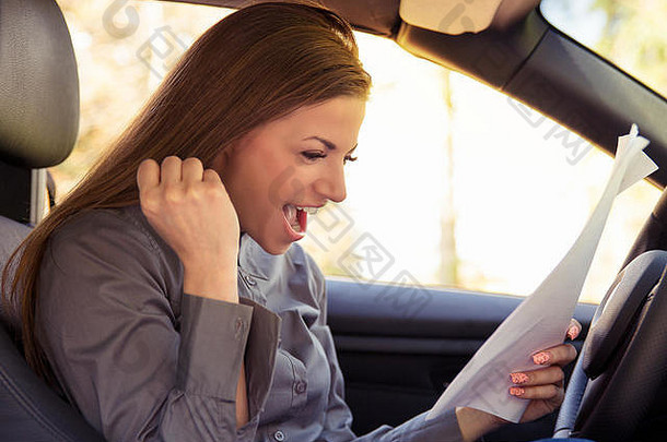 一位开朗的女士坐在车里，兴高采烈地研究着<strong>试卷</strong>，考试成功了。