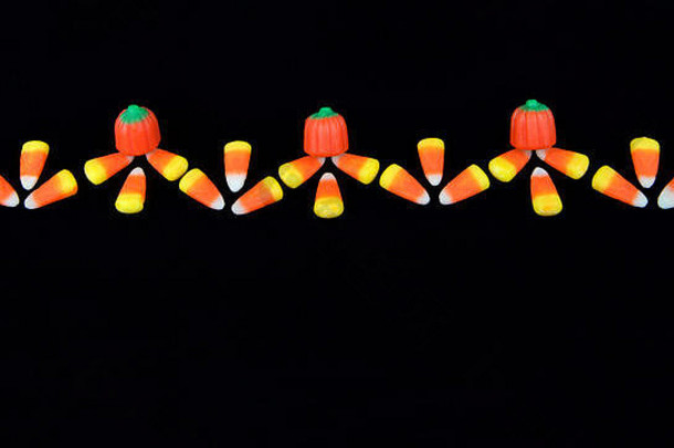 传统的万圣节糖果玉米和南瓜在黑色背景上对称排列，形成一个寄宿家庭