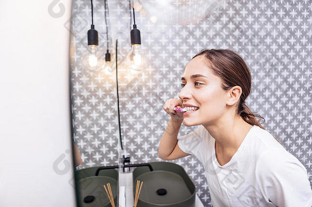一位黑发女子在她明亮的现代浴室刷牙