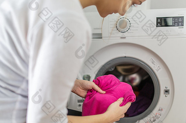 做家务年轻的女人洗衣把色彩斑斓的服装洗机浅景深颜色健美的图像