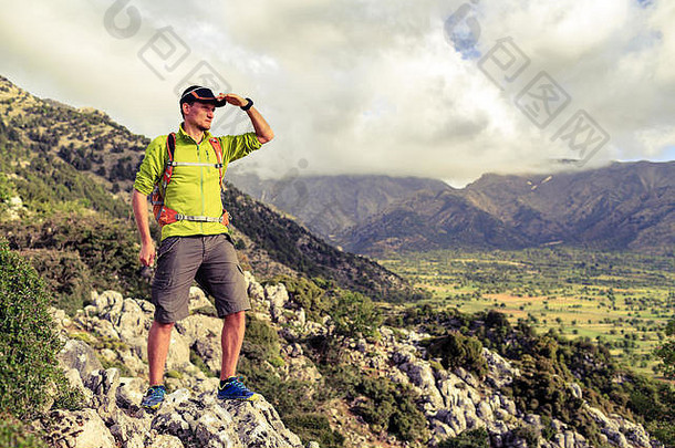 徒步旅行的人在看美丽的山脉和鼓舞人心的风景。徒步旅行者背着背包在岩石小径上徒步旅行，欣赏山谷的景色。他