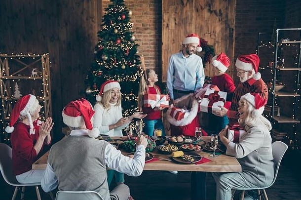圣诞快乐的圣诞聚会快乐的小孩子成熟的退休老人圣诞餐桌圣诞老人帽子男人手拿麻袋送礼物盒祝福
