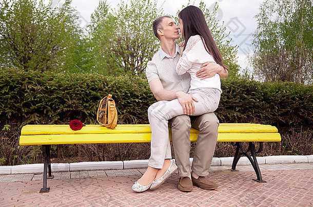 肖像夫妇红色的玫瑰接吻黄色的板凳上公园年轻的女人坐着的男<strong>朋友圈</strong>完整的长度