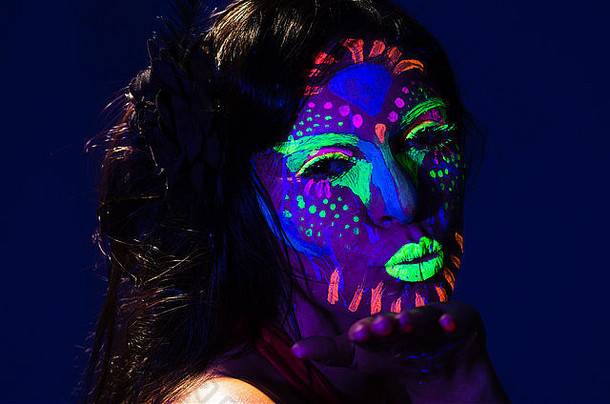 头像上的女人脸上涂着令人敬畏的夜光，蓝色和其他霓虹灯<strong>颜色搭配</strong>，背景模糊抽象，面对着摄像机