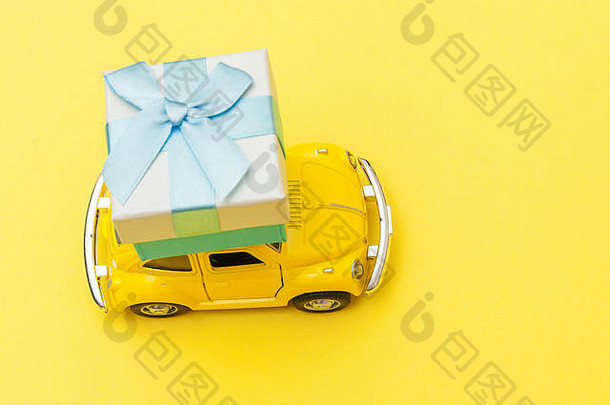简单设计黄色复古玩具车，在时尚的黄色背景上隔离车顶上的礼品盒。圣诞新年生日情人节庆祝活动呈现浪漫理念。