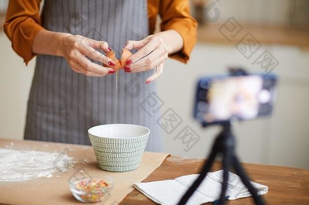 《空间》视频频道拍摄烘焙教程时，一位面目全非的年轻女子打碎鸡蛋的特写镜头