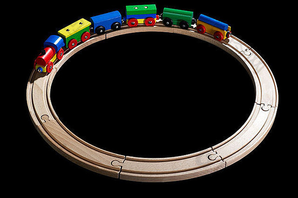 一辆彩色木制玩具火车在黑色背景的木制轨道上的摄影棚照片