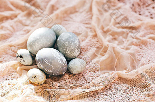 在阳光明媚的木头上，用质朴的面料制作时尚的复活节彩蛋。用灰色大理石涂上天然染料的现代彩色鸡蛋。复活节快乐，贺卡