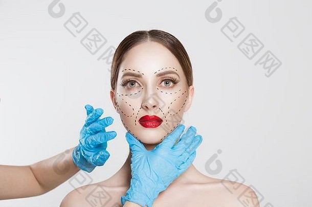 面部整容整形外科。医生外科医生手戴手套在女人脸上画皱纹线隔离白色背景。塑造皱纹