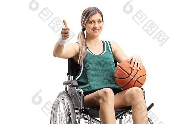 年轻的女人轮椅持有篮球显示拇指孤立的白色背景
