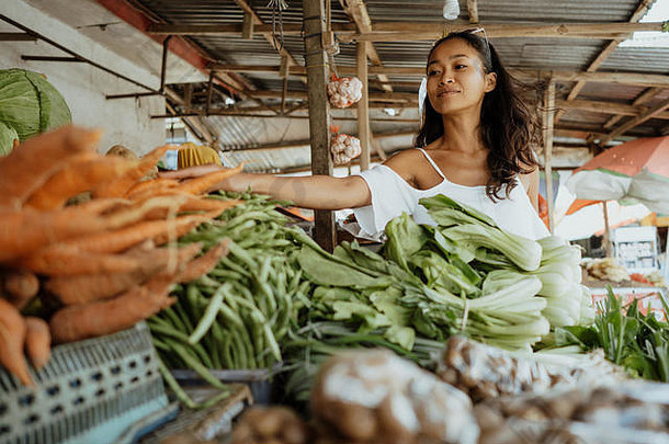 亚洲妇女在热带市场上摆姿势卖蔬菜和水果