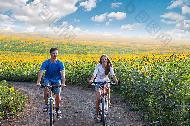 年轻夫妇在向日葵田骑自行车