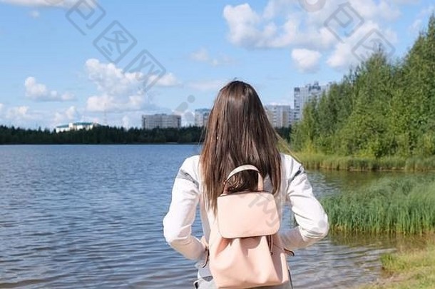 背着背包的黑发女孩欣赏着令人惊叹的美景。湖光山色。冒险、自由、生活方式
