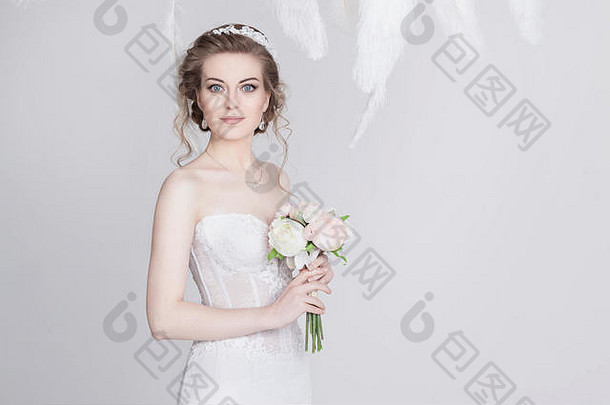 一位穿着奢华蕾丝婚纱的年轻梦幻新娘的肖像。她有一头美丽的深金色头发，一双蓝色的大眼睛和一双蓝色的眼睛