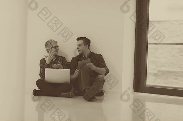初创企业和新的移动技术概念，年轻夫妇在现代明亮的办公室室内，在新cre上使用笔记本电脑和平板电脑